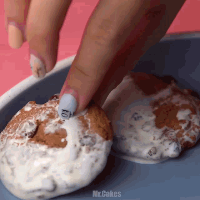 a close up of a person 's hand reaching for a cookie that says mr.cakes on it