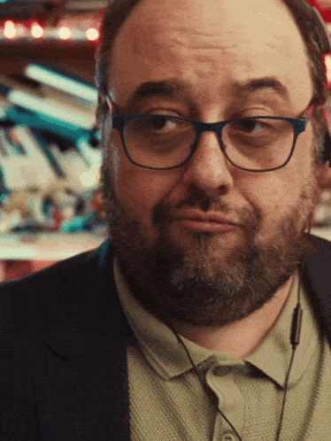 a man with glasses and a beard is wearing headphones around his neck