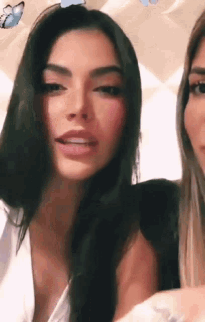 two women are sitting next to each other and one of them is wearing a white top .