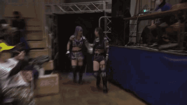 two women are standing next to each other in a dark room .