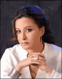 a woman wearing a white shirt and earrings is looking at the camera