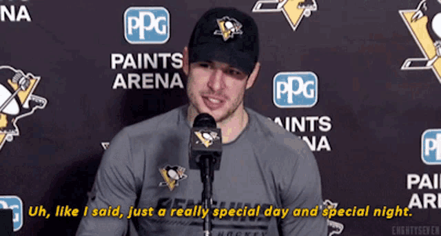 a man is talking into a microphone in front of a wall with ppg paints arena logos