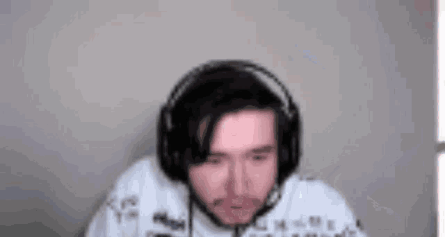 a man wearing headphones and a microphone is sitting in front of a wall .