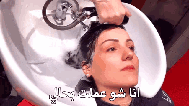 a woman is getting her hair washed in a sink with arabic writing on the bottom
