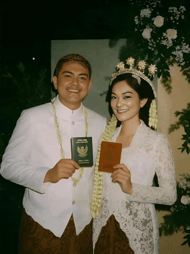 a bride and groom are posing for a picture and the bride is holding a passport with indonesia on it