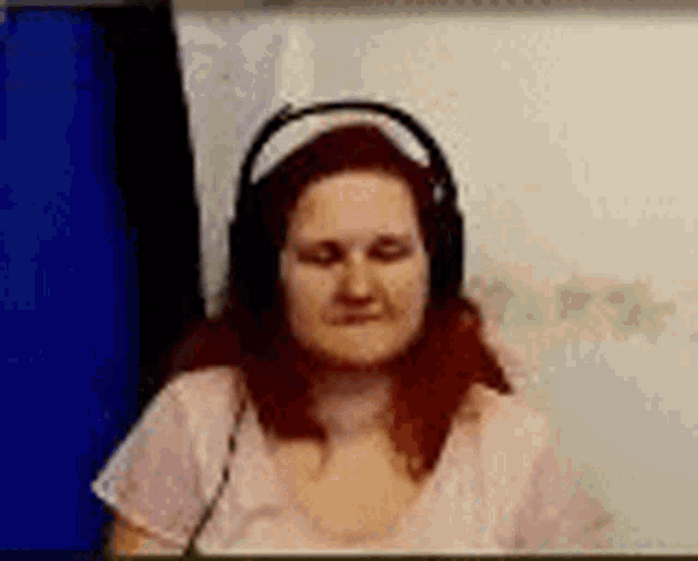 a woman wearing headphones and a pink shirt is sitting in front of a white board .