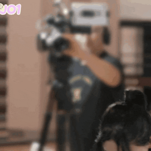 a blurry photo of a person holding a camera with the number 901 in pink