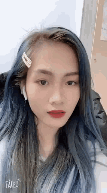 a woman with long blue hair is wearing headphones and a hair clip in her hair .