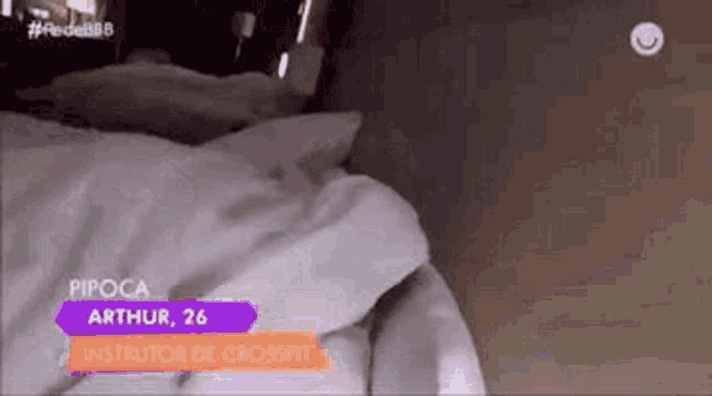 a person is laying on a bed with a sign that says ' pipoca arthur 26 ' on it .