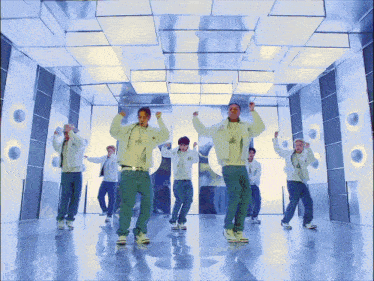 a group of young men are dancing in a room with a mirrored ceiling