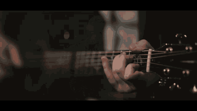 a close up of a person playing a guitar with their fingers