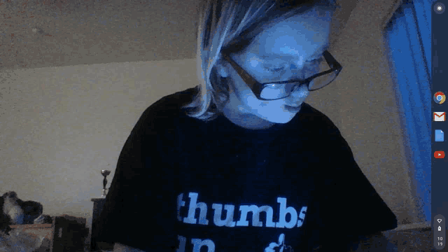 a girl wearing glasses and a shirt that says " thumbs in "