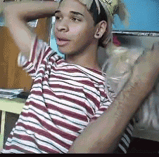 a young man wearing a striped shirt and a hat holds his arm over his head