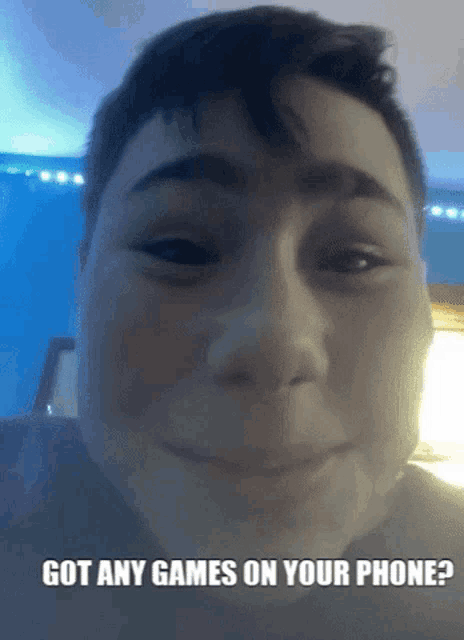a boy is smiling with the words got any games on your phone below his face