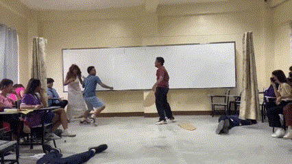 a group of people are dancing in a classroom with a whiteboard in the background .
