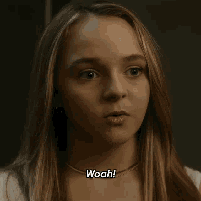 a girl with long hair says woah in a dark room