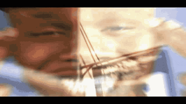 a close up of a person 's face with a blurred image of another person 's face in the background