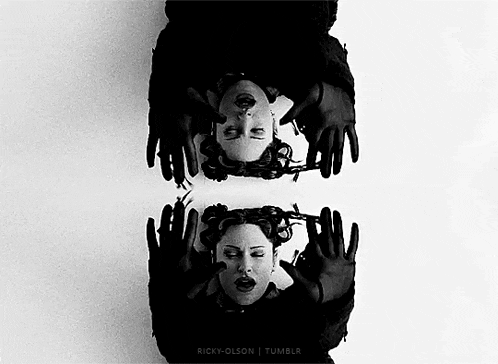 a black and white photo of two women laying on their backs with their hands on their faces .