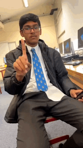 a man wearing glasses and a blue tie is giving a middle finger