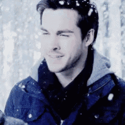 a man wearing a blue jacket and scarf is standing in the snow .