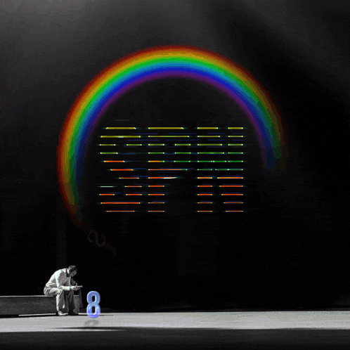 a man sits on a bench in front of a rainbow and the word spn