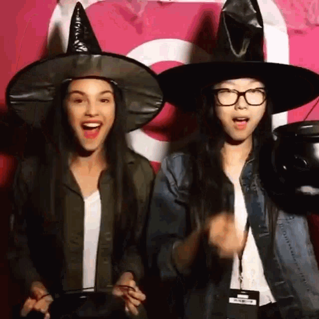 two women wearing witch hats are standing next to each other .