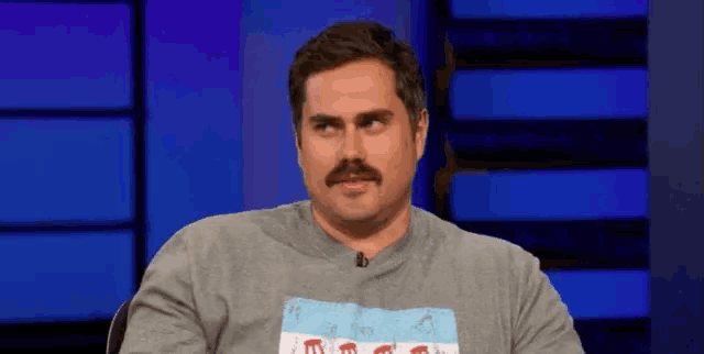 a man with a mustache is wearing a gray shirt with the word chicago on it .