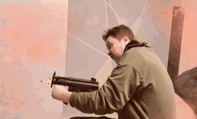 a man in a green hoodie is holding a gun with a red arrow coming out of it