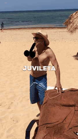 a shirtless man holding a microphone on a beach with the word juvileta above him