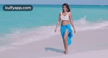 a woman in a blue skirt is walking on a beach .