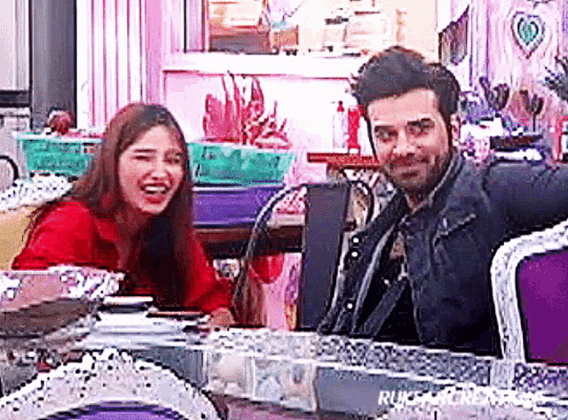 a man and a woman are sitting at a table laughing and smiling .