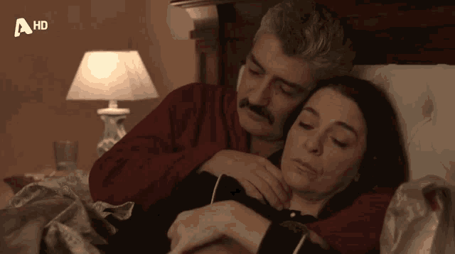 a man and a woman laying in bed with a hd logo on the bottom