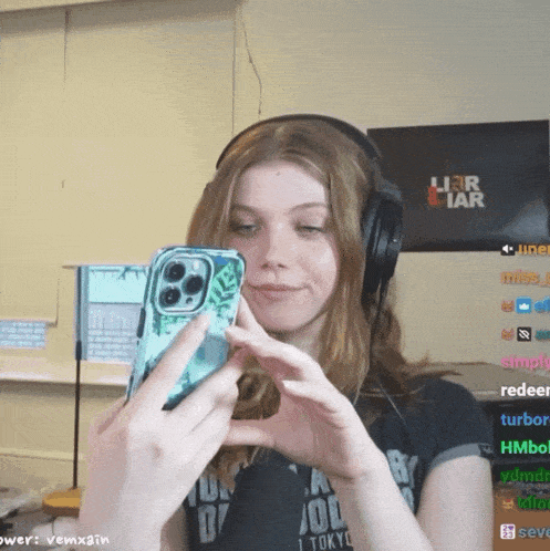 a girl wearing headphones takes a picture of herself with her phone