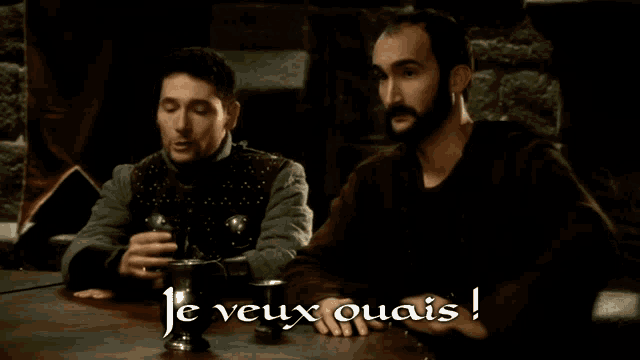 two men sitting at a table with the words je veux quais written on the bottom