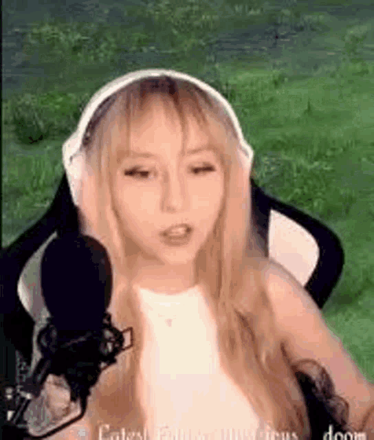 a woman wearing headphones and a microphone is sitting in a chair in a field .