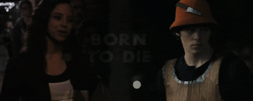 a man in an orange hat stands next to a woman with the words born to die behind him