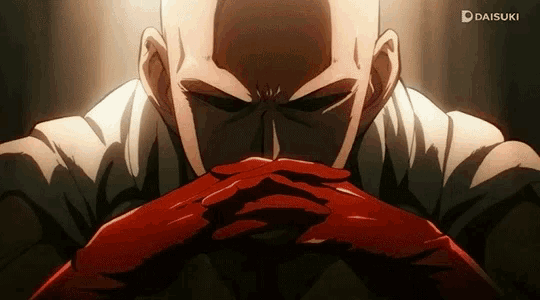 a bald man in a white shirt and red gloves is sitting with his hands folded in front of his face .