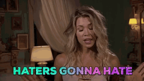 a woman is sitting on a bed and says haters gonna hate