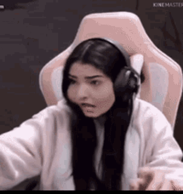 a woman is sitting in a pink chair wearing headphones and making a funny face .