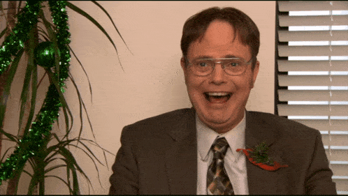 a man in a suit and tie is smiling in front of a plant