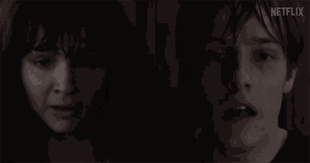 a man and a woman are standing next to each other in a dark room .