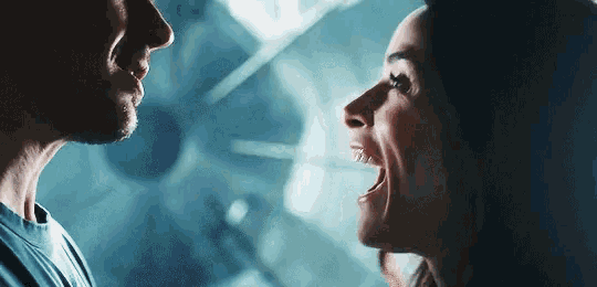 a man and a woman are looking at each other with their mouths open in a dark room .