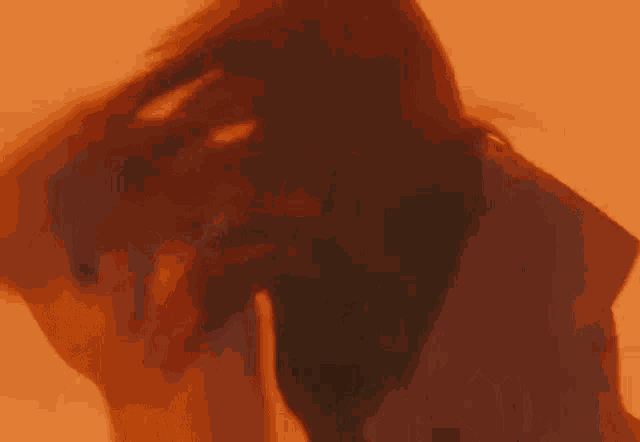 a woman with long red hair is dancing in a dark room with a red background .