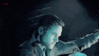 a man is standing in a dark room with his arms outstretched .