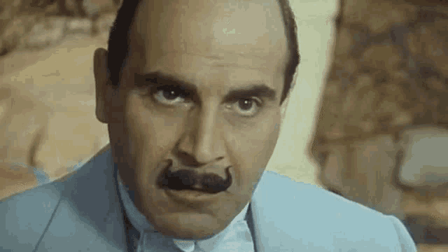 a close up of a man with a mustache in a suit .