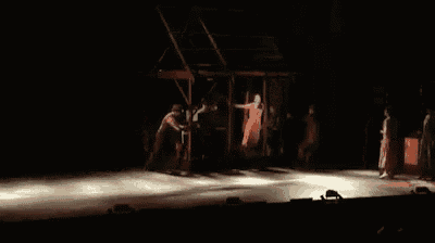 a woman in an orange dress is dancing on a stage while a man plays a piano .