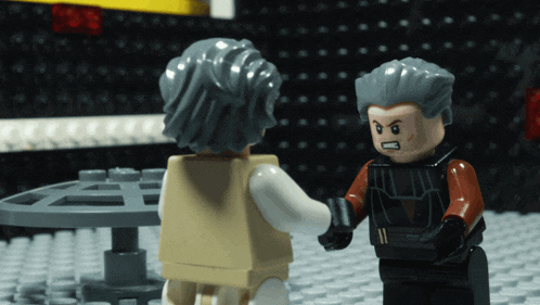two lego figures are shaking hands and one has a gray haired head