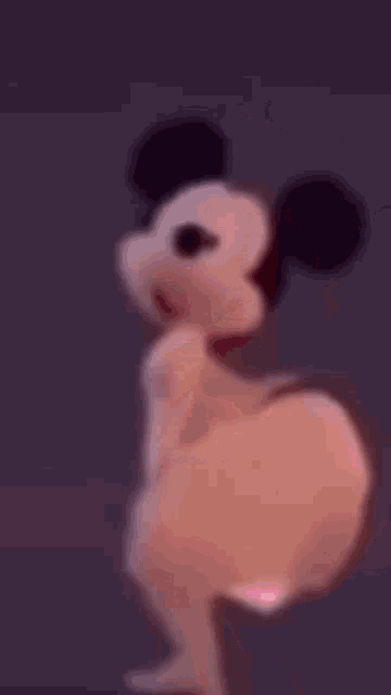 a naked mickey mouse is dancing in a purple background .