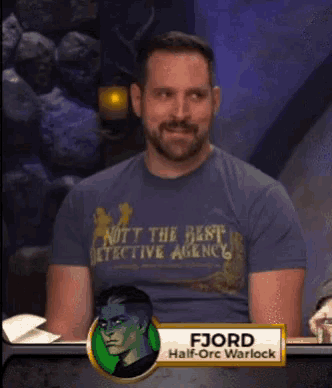 a man wearing a blue shirt that says " nott the best detective agency "
