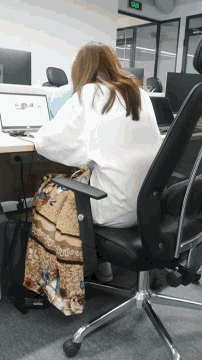 a woman sits in an office chair with a blanket on her lap and a laptop on her lap